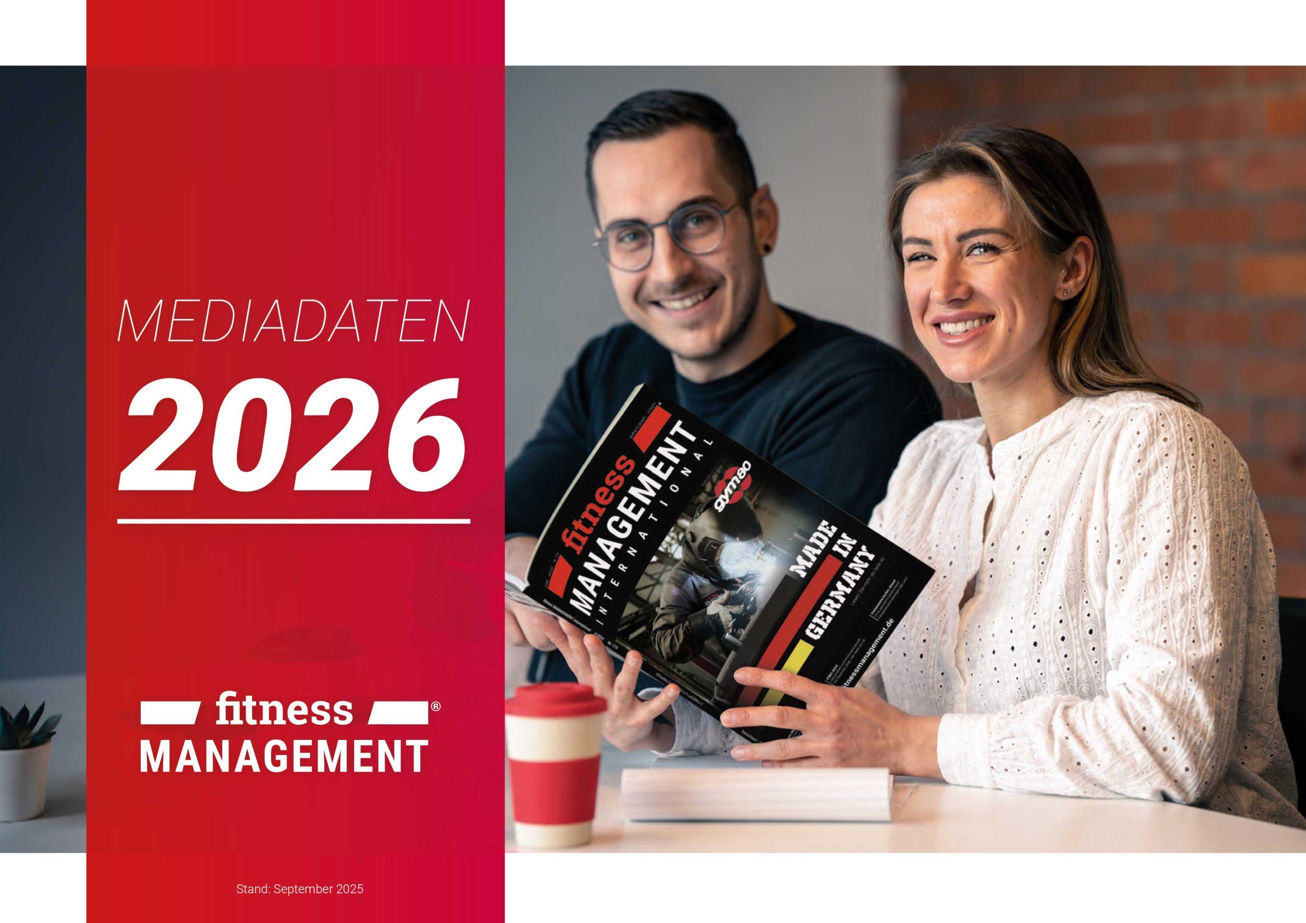 Titelmotiv der Mediadaten 2026 von fitness MANAGEMENT: Zwei Personen sitzen an einem Tisch, lächeln in die Kamera und halten gemeinsam ein Exemplar des Magazins fitness MANAGEMENT international.