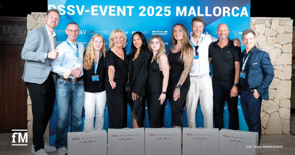 Gruppe von Personen posiert vor einer blauen Wand mit Event-Branding, vor ihnen stehen mehrere InBody-Geräte.