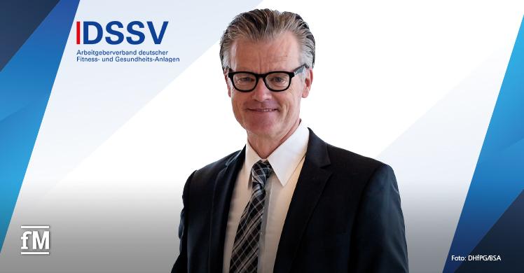 DSSV Kommentar Ralf Capelan Porträt von Ralf Capelan im Anzug mit DSSV-Logo im Hintergrund.