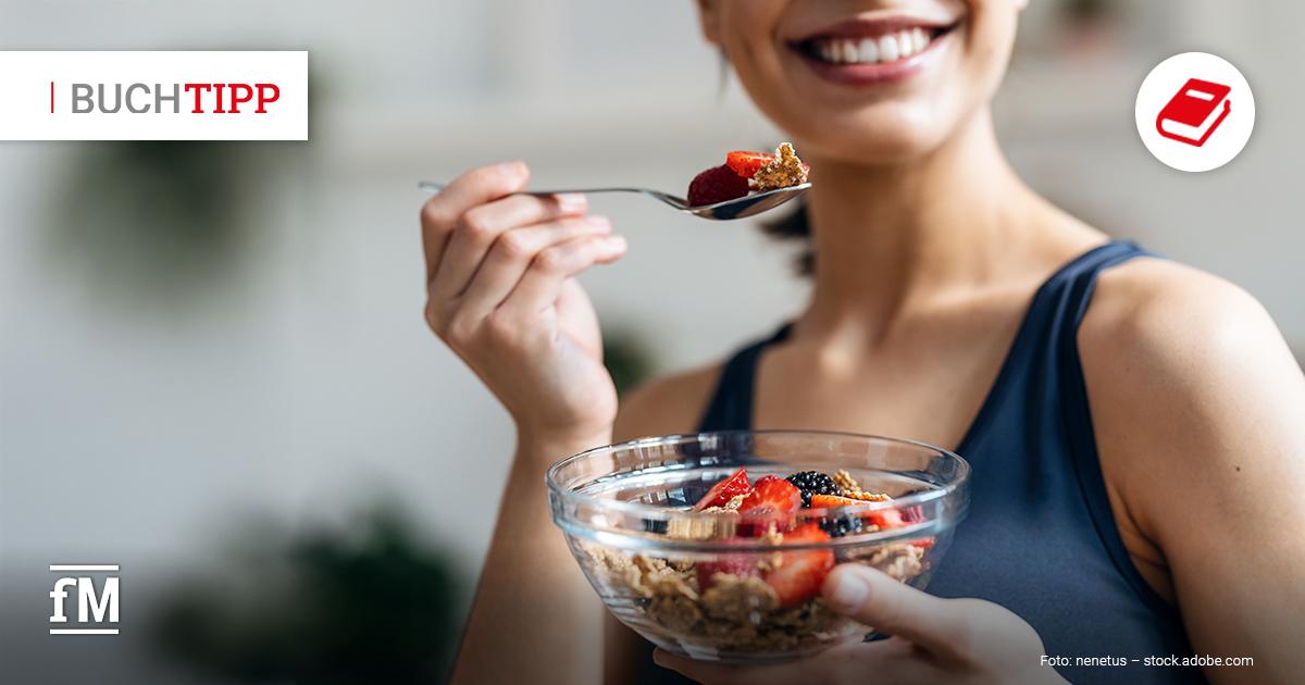 Frau isst lächelnd Müsli und frische Beeren aus einer Schale.