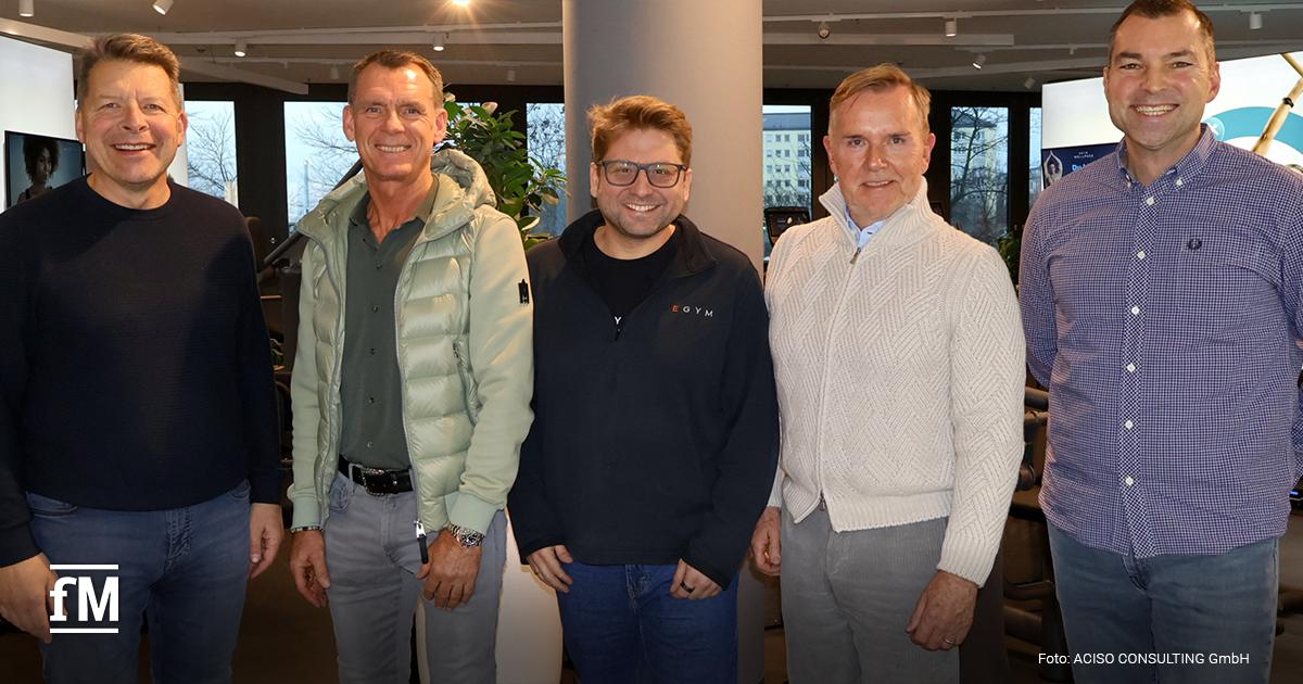 Fünf Branchenvertreter stehen gemeinsam in München für ein Meeting zusammen und blicken in die Kamera