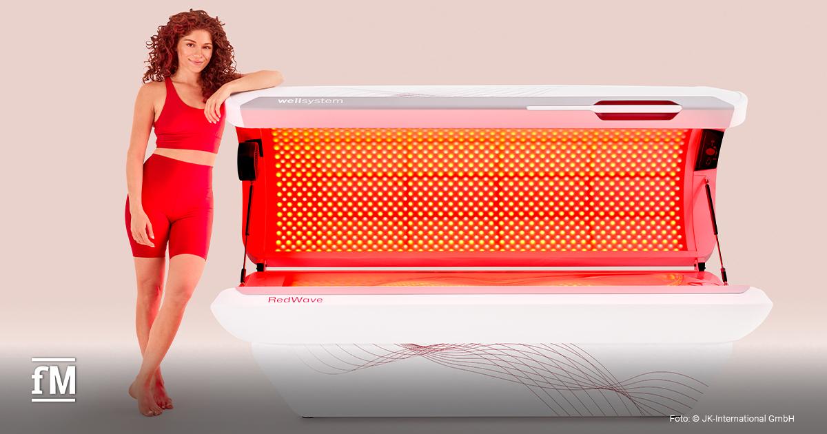 Frau in roter Sportbekleidung steht neben dem geöffneten wellsystem RedWave mit intensivem Rotlichtmodul