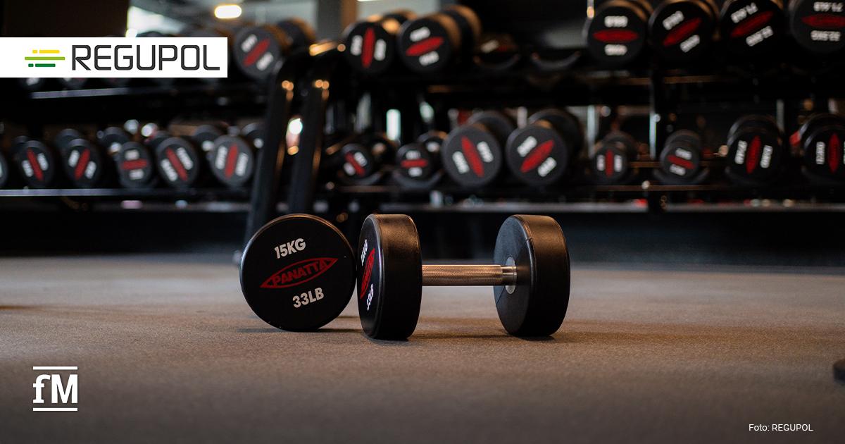 Geräte- und Hantelbereich mit grauem Fitnessboden und roten Trainingsgeräten.