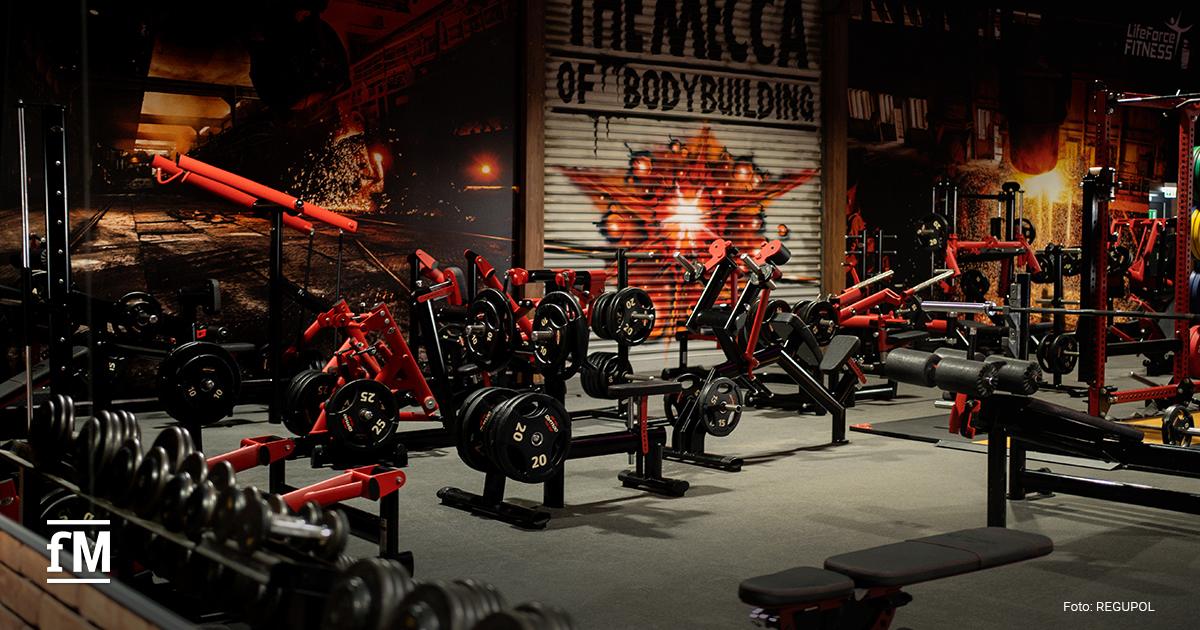 Krafttrainingsgeräte in einem Fitnessbereich auf grauem Boden.