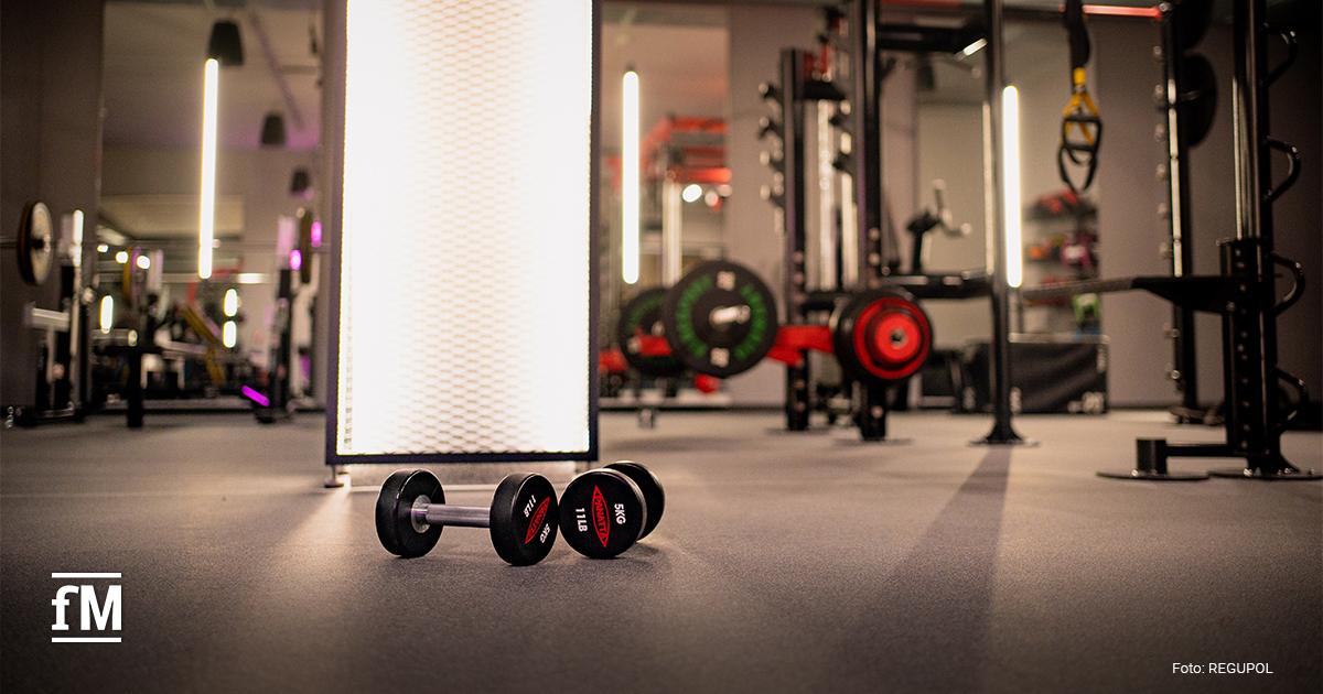 Kurzhanteln liegen auf grauem Fitnessboden in einem Trainingsraum.