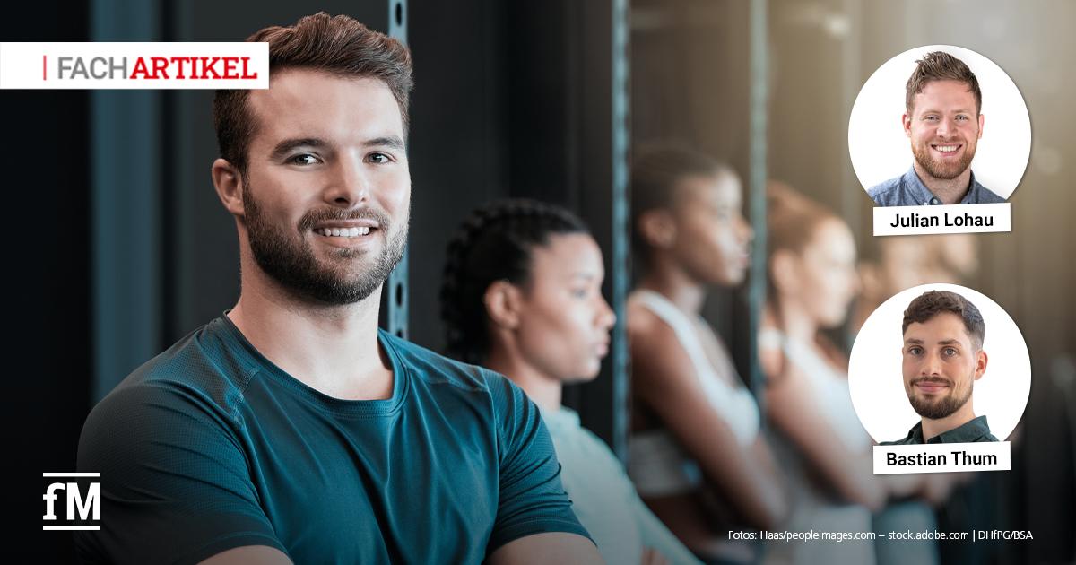 Markenbotschafter Trainer Ein Trainer steht mit verschränkten Armen im Vordergrund eines Fitnessstudios, im Hintergrund trainieren weitere Personen an Geräten