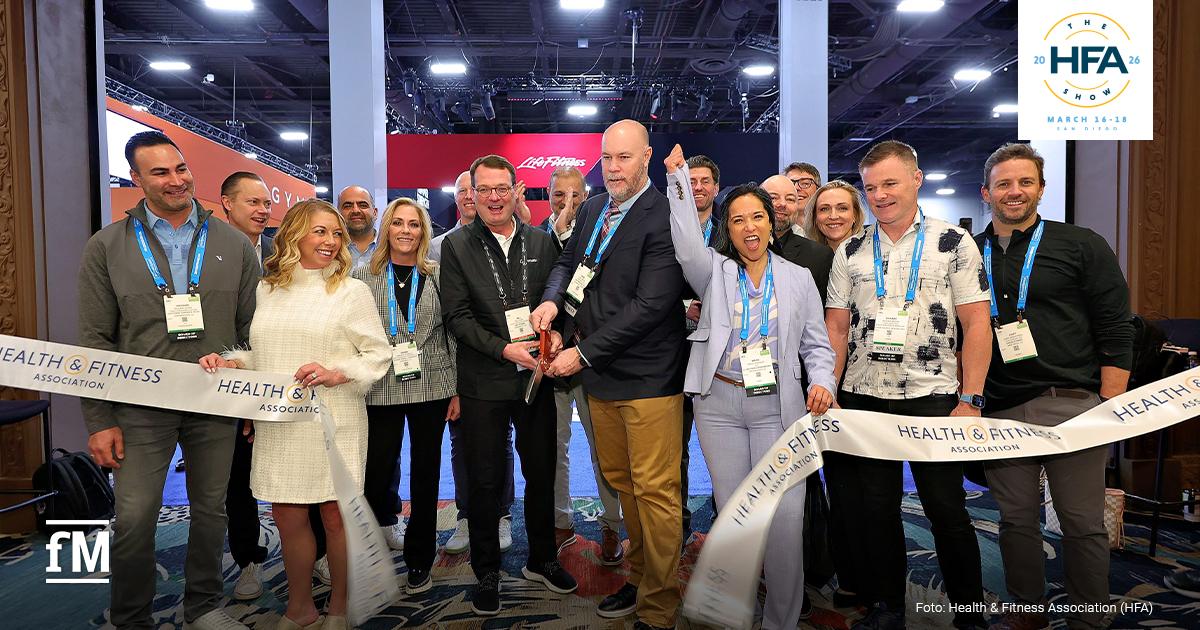 Gruppe von Personen bei einer Banddurchschneidung mit HFA-Beschriftung in einer Messehalle (San Diego Convention Center).