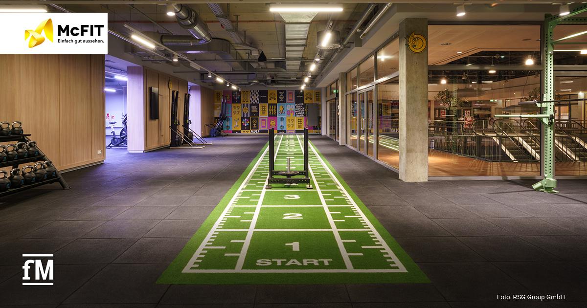 Moderner McFIT-Trainingsbereich mit grünem Indoor-Sprinttrack, Gewichtsschlitten und offener Fläche für funktionelles Training
