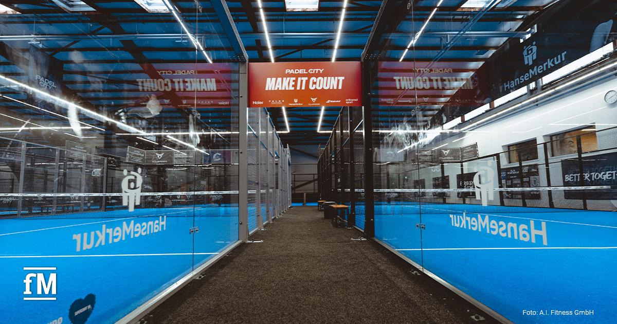 Blick durch einen Gang zwischen zwei Padel-Courts mit Glaswänden und dem Schriftzug „Make it count“ in der PadelCity-Halle