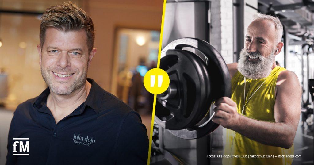 Porträt eines Mannes mit verschränkten Armen in einem Fitnessstudio in Hamburg; im Hintergrund Trainingsfläche und Logo der juka dojo Fitness Clubs