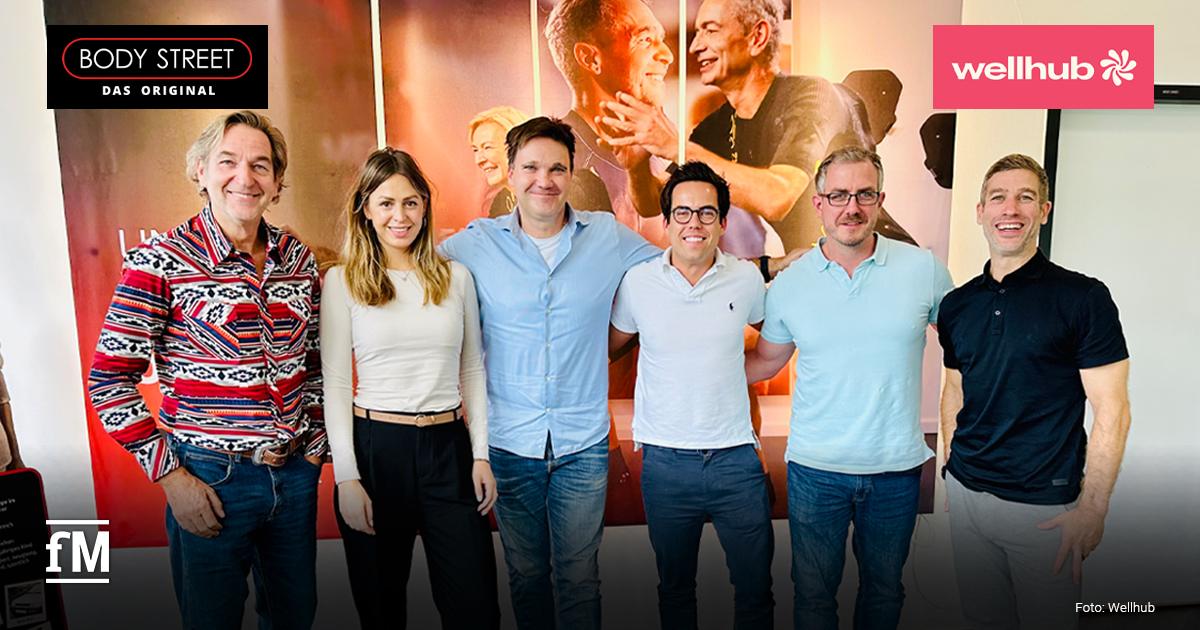 Gruppenfoto von sechs Personen aus dem Fitness- und Gesundheitsbereich, die nebeneinander in einem Studio stehen und in die Kamera lächeln