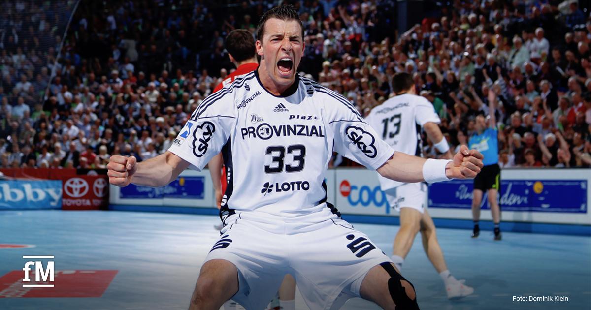 Ein Handballspieler (Dominik Klein) jubelt mit erhobenen Fäusten auf dem Spielfeld. Im Hintergrund ist eine volle Arena mit Zuschauern zu sehen
