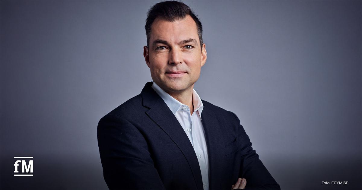 Mann mit Brille im Anzug mit Krawatte vor hellem, unscharfem Hintergrund in einem Innenraum