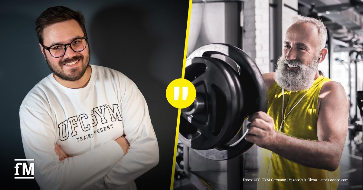 Performance is Health Porträt eines Mannes in einem Innenraum mit warmem Licht; im Vordergrund lächelnd, im Hintergrund unscharfer Raum mit Glasflächen