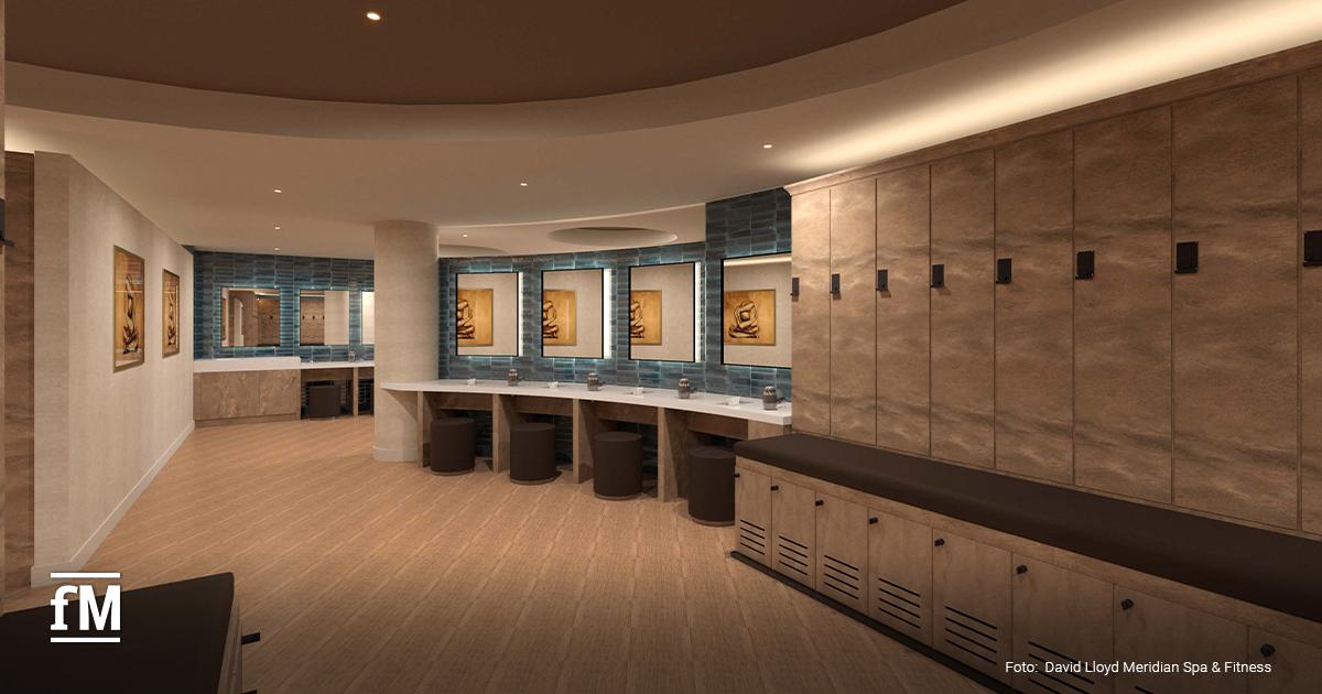 Umkleideraum mit Holzspinden, Waschplätzen mit Spiegeln, Hockern und beleuchteten Wandbildern.