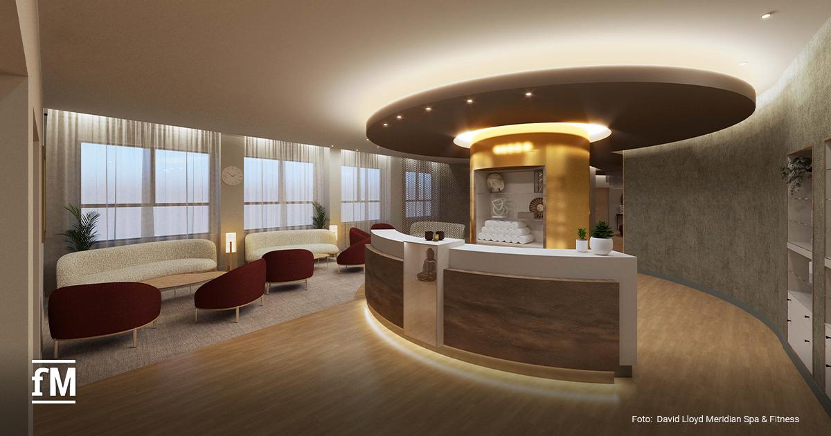 Runder Empfangstresen mit goldener Säule, Sitzmöbeln und großen Fenstern in einem Spa-Bereich.