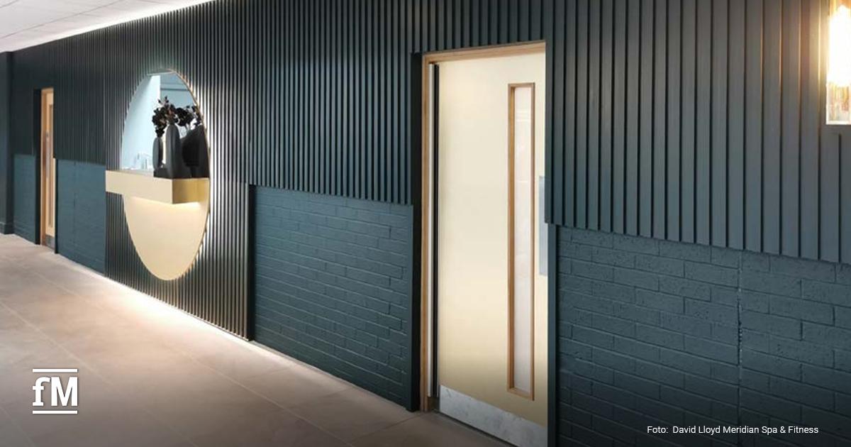 Flur mit dunkelgrüner Wandverkleidung, runder Wandnische mit Vase, Türen zu Räumen und heller Deckenbeleuchtung.