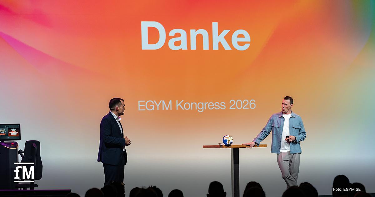 Bühne mit großer Leinwand und Schrift „Danke – EGYM Kongress 2026“, zwei Männer stehen vor Publikum