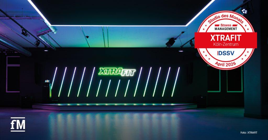 Moderner Kursraum mit beleuchteter Bühne, XTRAFIT-Schriftzug und auffälligem Lichtdesign.