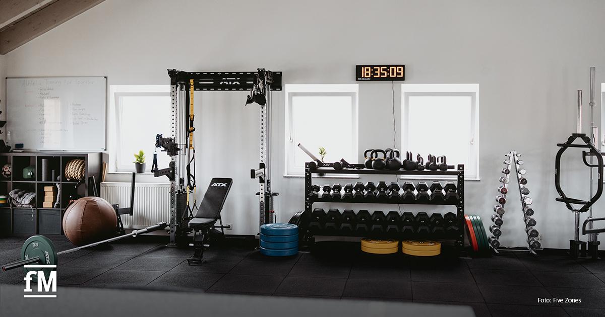 Modern eingerichtetes Trainingsstudio mit freiem Gewicht, Medizinball und Kraftstation.