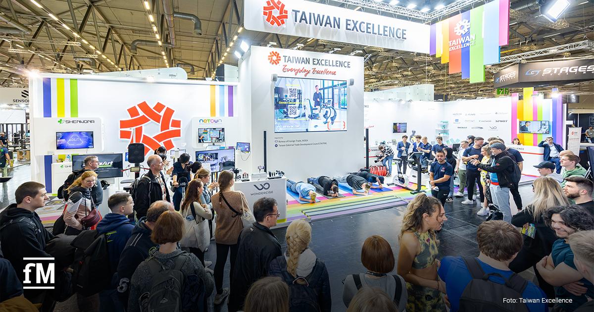 Taiwan Excellence Innovationen FIBO 2026 „Taiwan Excellence“-Messestand mit vielen Besuchenden; in der Mitte machen mehrere Personen auf bunten Matten Fitnessübungen.