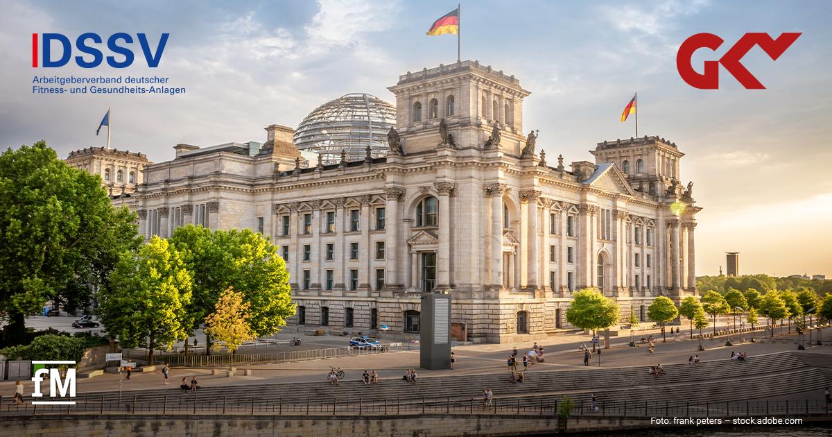 Ansicht des Reichstagsgebäudes in Berlin bei warmem Abendlicht, mit Glaskuppel, mehreren Deutschlandflaggen und Logos von DSSV und GKV im Bild.