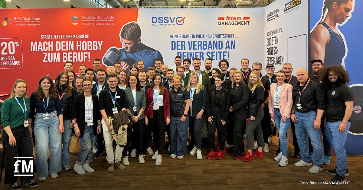 Das Team von DSSV, fM, DHfPG und BSA-Akademie auf der FIBO 2026 in Köln Große Gruppenaufnahme vor einer Messestand-Wand: etwa 40–50 Personen unterschiedlichen Alters und Geschlechts stehen dicht beieinander und lächeln in die Kamera
