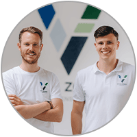 Zwei Männer in weißen T-Shirts stehen vor eine rWand mit einem angeschnittenen Logo