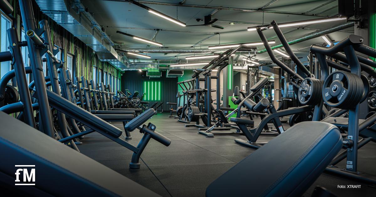 Weitläufiger Krafttrainingsbereich mit Hantelbänken, Maschinen und dunklem, hochwertigem Studiodesign.