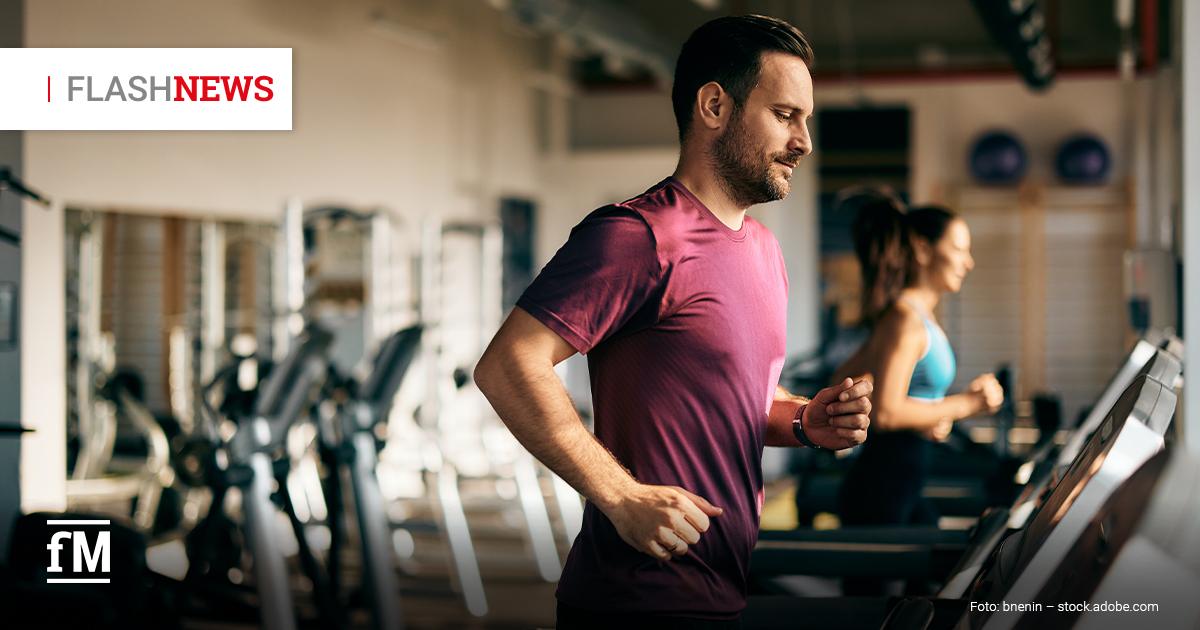 Fitness Flash News #05/2026 KW 22 Mann in bordeauxfarbenem Sportshirt joggt auf einem Laufband im Fitnessstudio, im Hintergrund läuft eine weitere Person auf einem zweiten Laufband. Oben links steht „FLASHNEWS“.