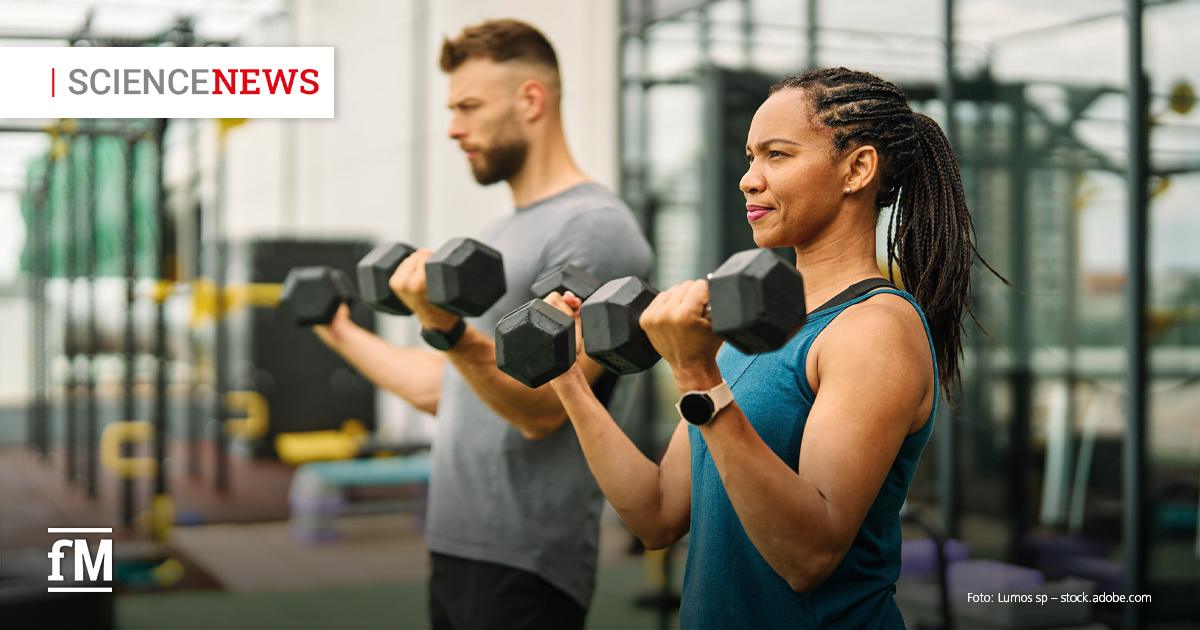 Science News: ACSM-Positionspapier zu Krafttraining Im Vordergrund führt eine Frau in blauem Sportoberteil mit zwei Kurzhanteln eine Bizepscurl-Bewegung aus. Links dahinter trainiert ein Mann mit Kurzhanteln. Im Hintergrund befinden sich Trainingsgeräte in einem Fitnessstudio. Oben links steht der Schriftzug „SCIENCE NEWS“, unten links das Logo „fM“.