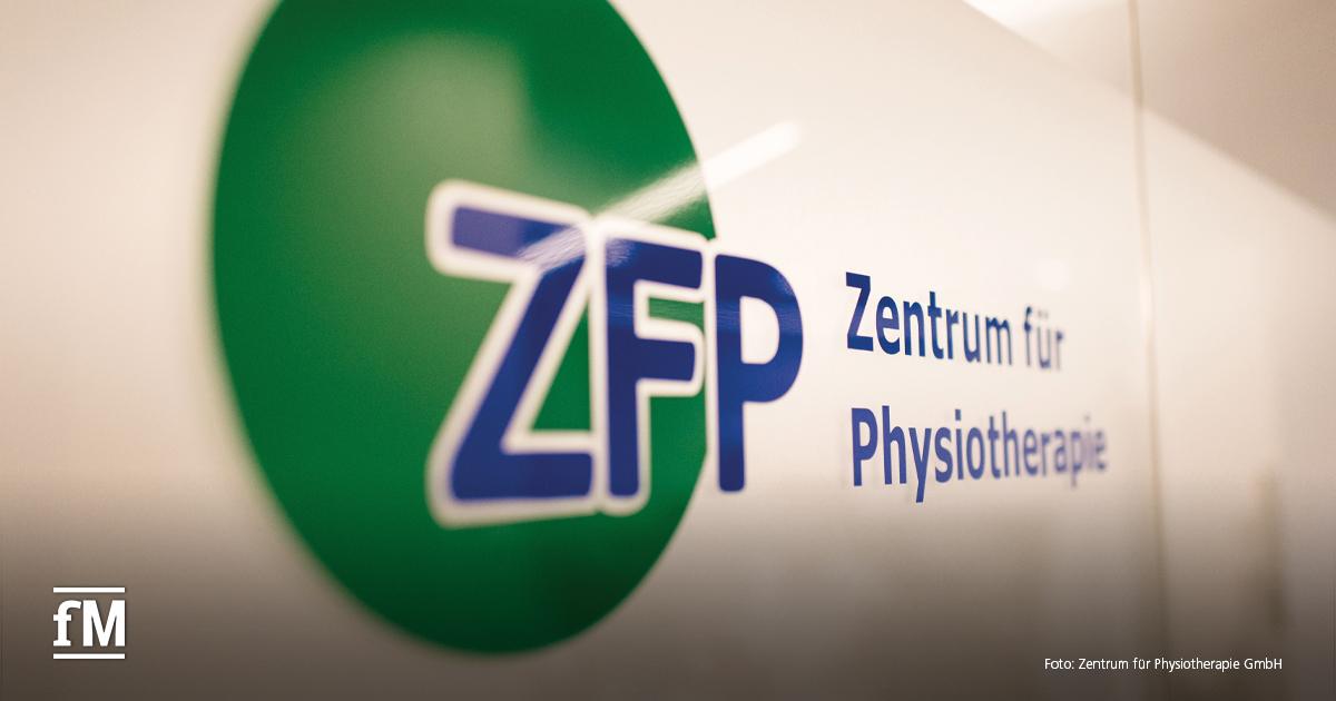 Nahaufnahme eines Wandlogos mit grünem Kreis und blauem Schriftzug „ZFP Zentrum für Physiotherapie“.