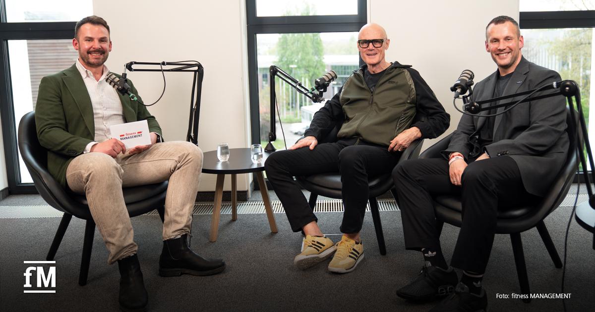Les Mills Group Fitness Janosch Marx, Phillip Mills und Jens Schulze sitzen zu einer Podcastaufnahme mit Mikrofonen in schwarzen Sesseln.