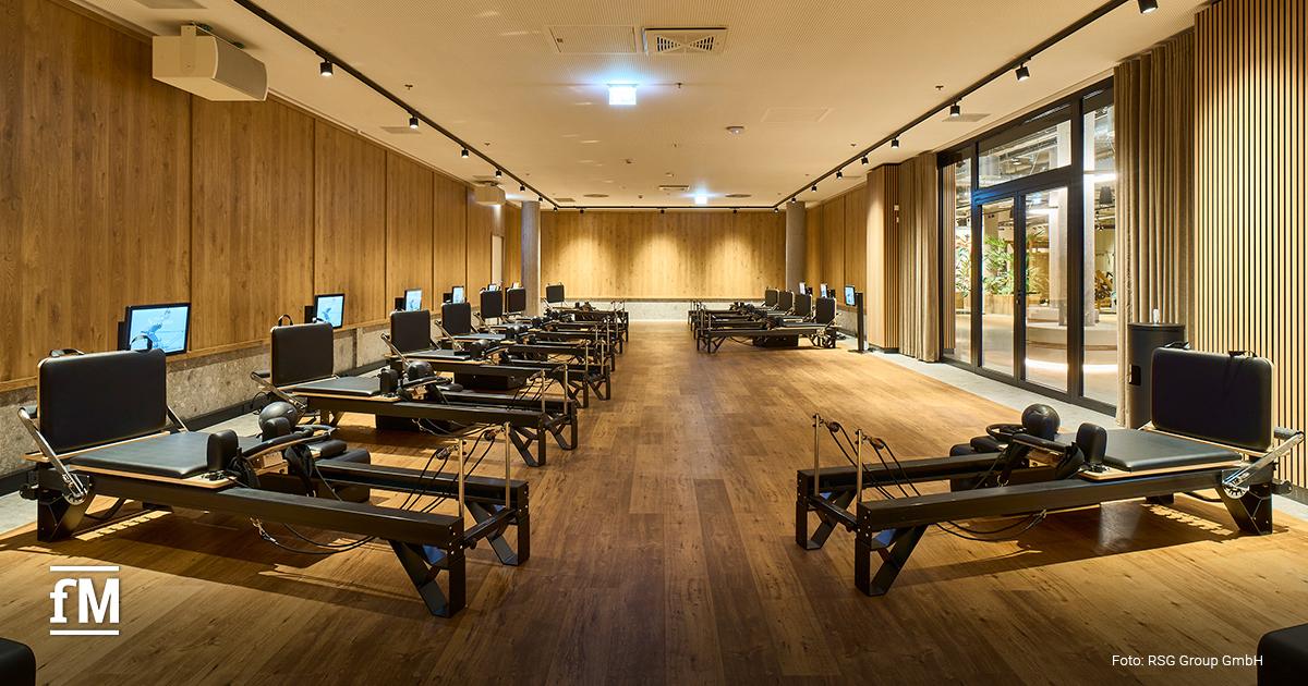 Reformer-Pilates-Raum mit mehreren Trainingsbänken und Monitoren