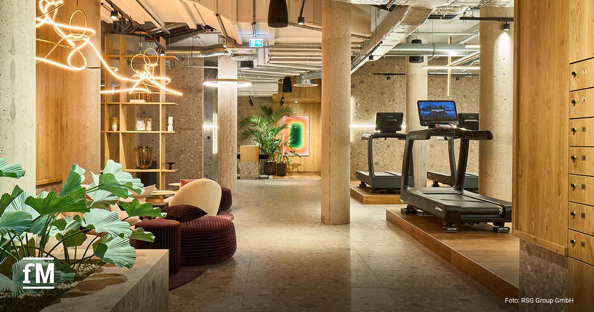Loungebereich mit Sitzmöbeln, Pflanzen und Laufbändern im Fitnessclub
