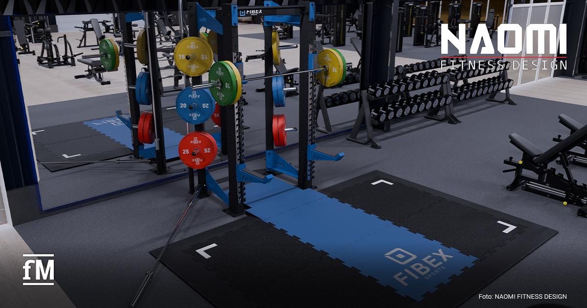 FIBEX Sports Aus erhöhter Perspektive ein dunkel gestalteter Fitnessraum mit blauschwarzem FIBEX-Rack mittig, Langhantel mit grünen und gelben Gewichtsscheiben, roten und blauen Gewichtsscheiben an den seitlichen Ablagen, schwarzer und blauer Bodenfläche mit FIBEX-Schriftzug vorn rechts, Kurzhantelablagen rechts im Hintergrund, Trainingsgeräten links im Hintergrund, NAOMI FITNESS DESIGN-Schriftzug oben rechts, fM-Logo unten links und Foto: NAOMI FITNESS DESIGN unten rechts.