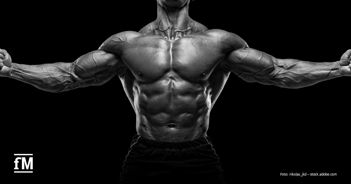 Die nächste Generation Bodybuilding Muskulöser Oberkörper eines Bodybuilders mit ausgestreckten Armen vor schwarzem Hintergrund.