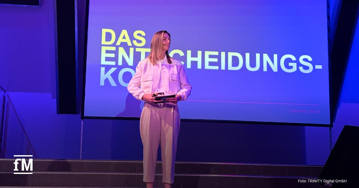 Eine Frau steht auf einer Bühne vor einer großen Leinwand
