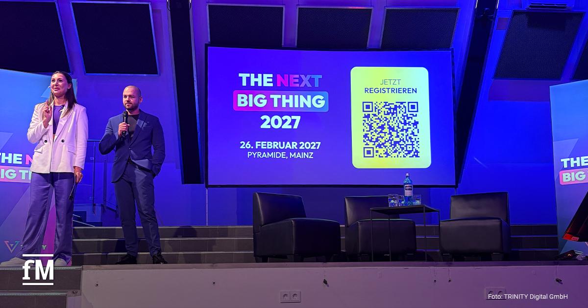 Zwei Personen stehen mit Mikrofonen auf einer Bühne. Auf der Leinwand stehen „THE NEXT BIG THING 2027“, „26. FEBRUAR 2027“, „PYRAMIDE, MAINZ“ und „JETZT REGISTRIEREN“ neben einem QR-Code.