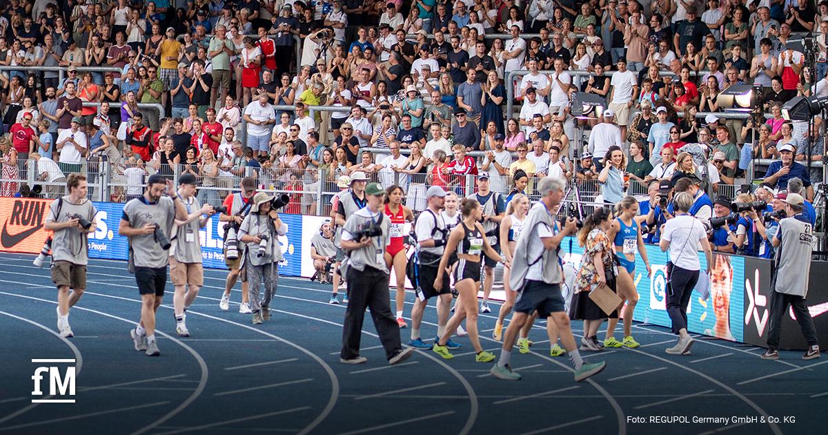 Athletinnen, Medienvertreter und Publikum an der blauen Laufbahn im Bochumer Lohrheidestadion.