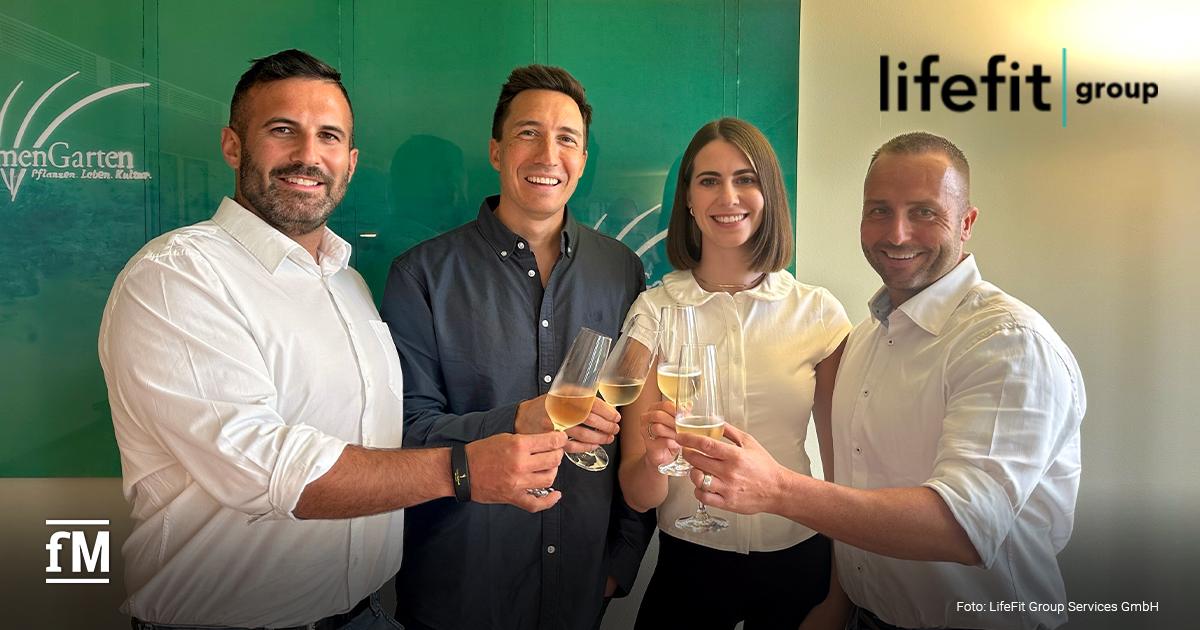 LifeFit Group Fitness Sigmaringen Vier Personen (von links Massimo Vicino, Christophe Collinet, Jasmin Tandari und Michael Maute) stoßen in einem Raum mit Sektgläsern an