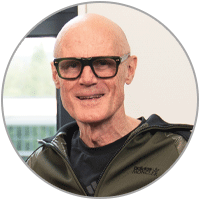 Porträt von Phillip Mills mit schwarzer Brille und dunkler Jacke