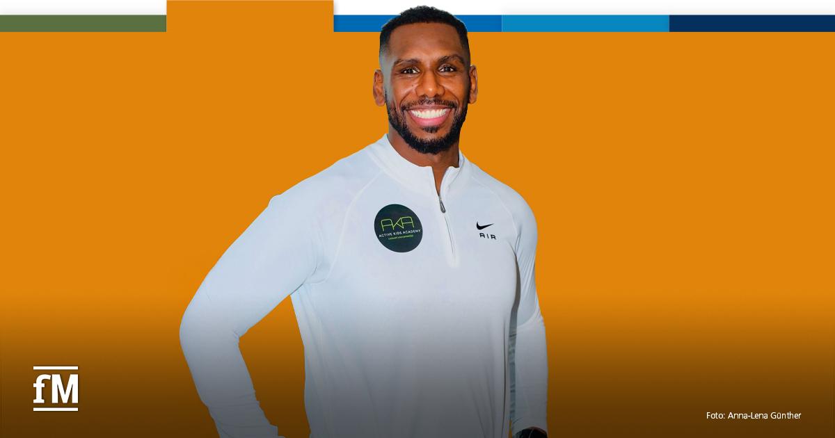 Welday Mebrahtu DHfPG Lächelnder Mann in weißem Sportoberteil vor orangefarbenem Hintergrund mit fM-Logo.