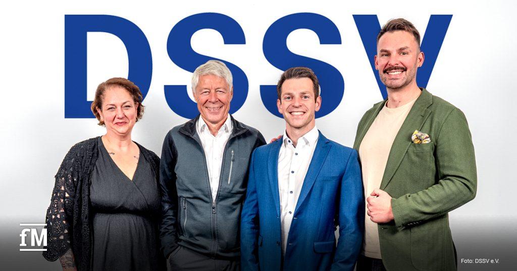 Vier Personen stehen vor einem großen blauen DSSV-Schriftzug.