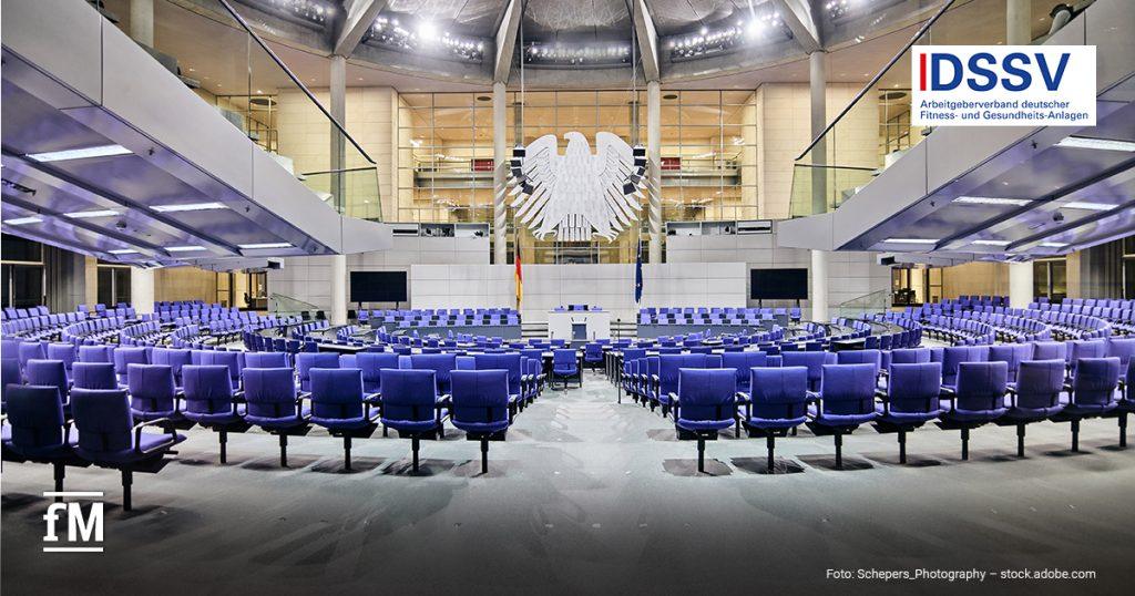 Großer Plenarsaal mit blauen Sitzreihen, Rednerpult und Bundesadler unter einer gläsernen Kuppel und DSSV-Logo rechts oben.