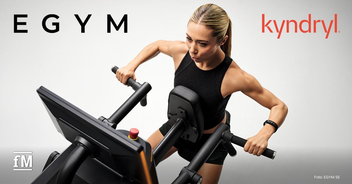 EGYM und Kyndryl Sportlerin trainiert an einem schwarzen Fitnessgerät mit Display und beweglichen Griffen.