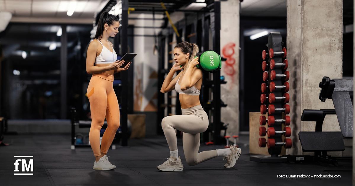 Erfolg durch Personal: Diagnostik und Trainingsplanung Trainerin begleitet eine Sportlerin beim Ausfallschritt mit einem Medizinball