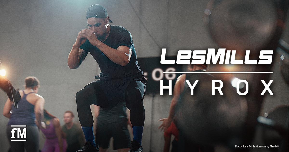 CEREMONY HYROX Australien Ein Mann steht auf einer Plyo-Box, im Hintergrund sind weitere Trainierende und Les-Mills-/HYROX-Logos zu sehen.