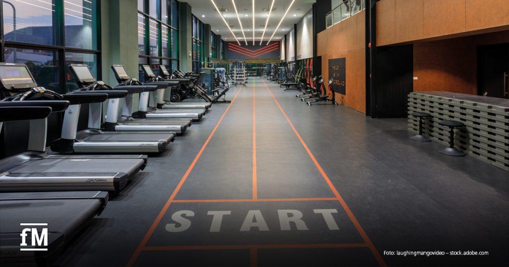 Moderne Trainingsfläche mit Laufbändern, Kraftgeräten und markierter Laufbahn.
