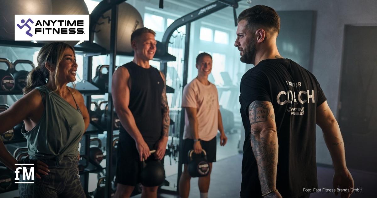 Anytime Fitness Karriere Deutschland Coach spricht mit drei Personen im Trainingsbereich eines Anytime-Fitness-Clubs